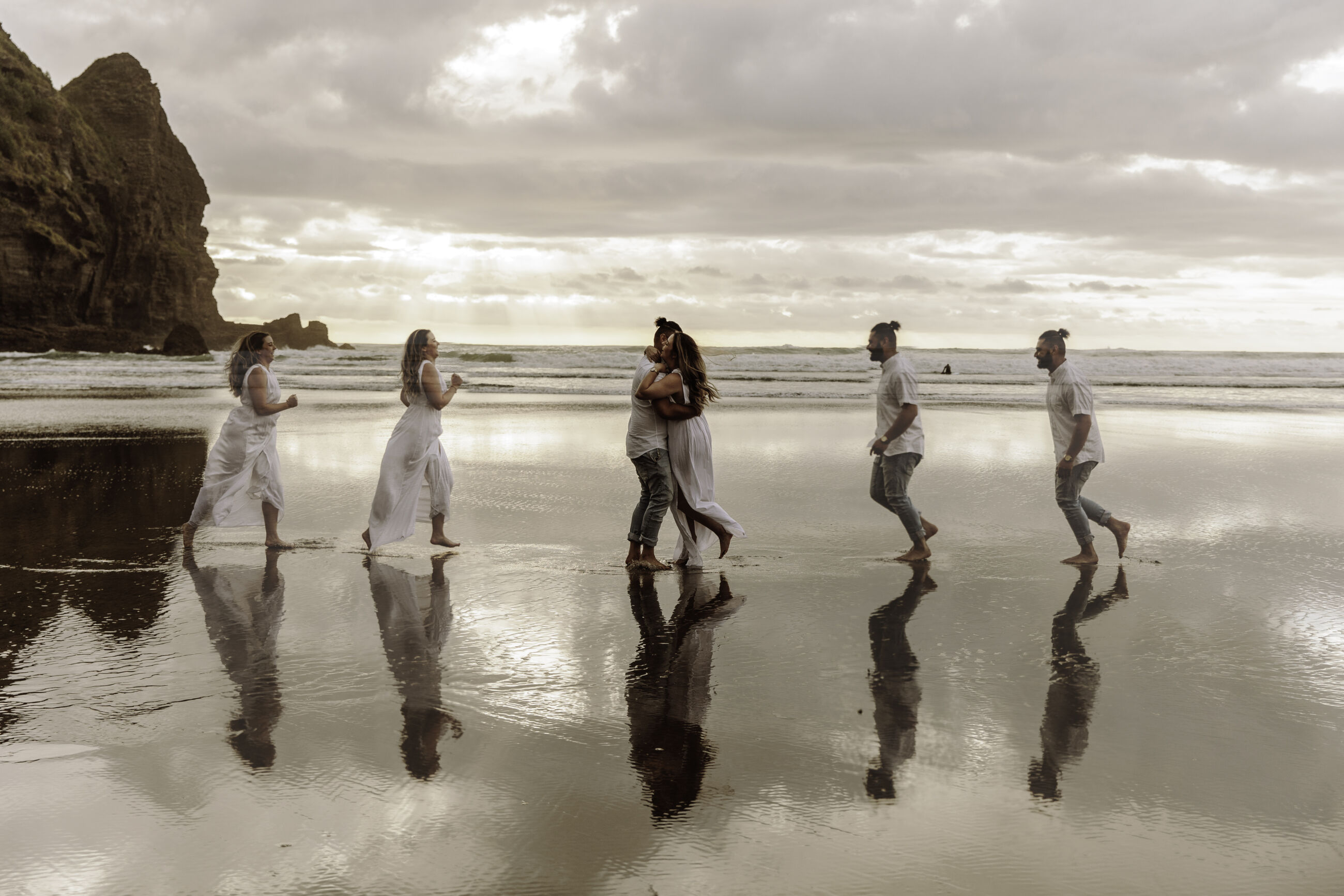 Couple running towards each other at Piha Beach